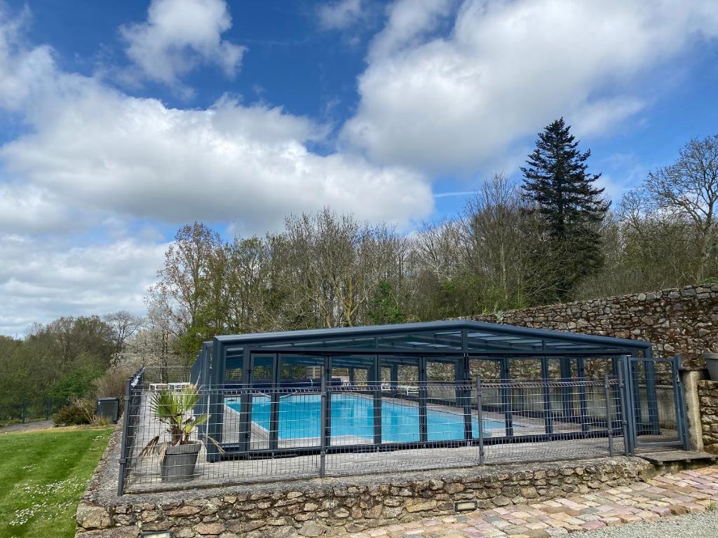 a swimming pool in a pavilion next to a stone wall at Maison d'hôtes & Gîtes Domaine de la Garaye in Dinan