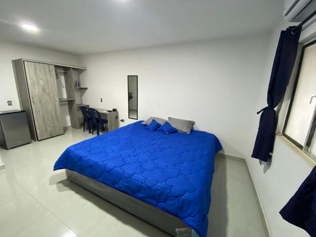 a bedroom with a bed with a blue comforter at Comfortable apartment very close to the airport in Cúcuta