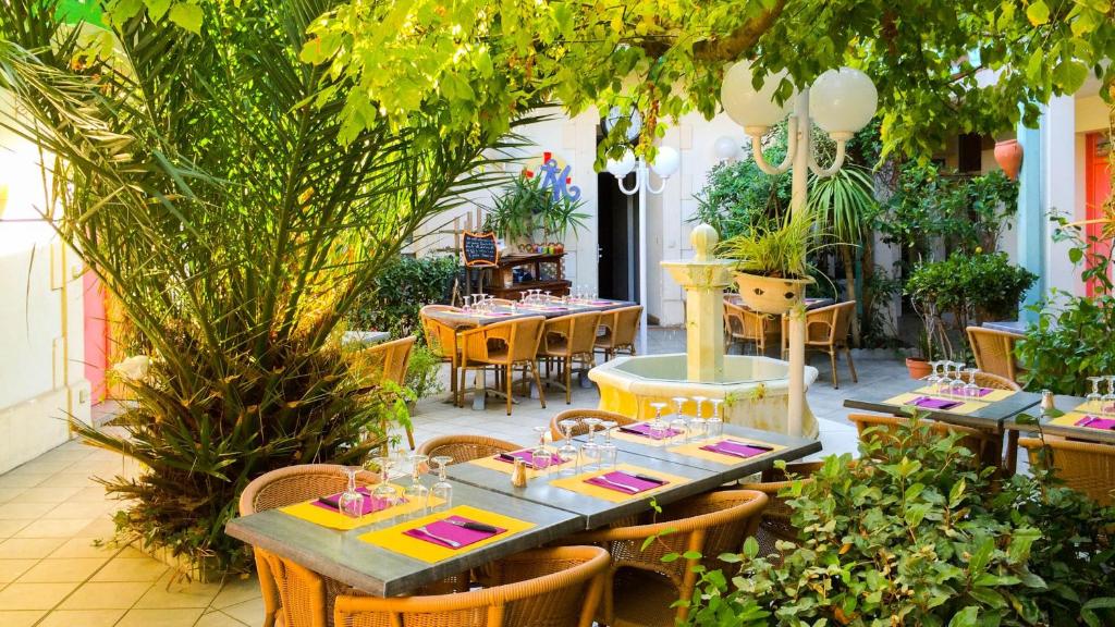 アルカションにあるHôtel Orange Marineの庭園内のテーブルと椅子付きのレストラン