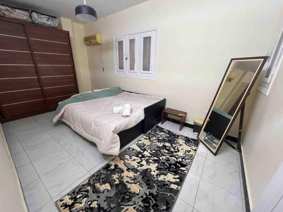 een slaapkamer met een bed, een spiegel en een tapijt bij Cozy Heliopolis Apt in Caïro