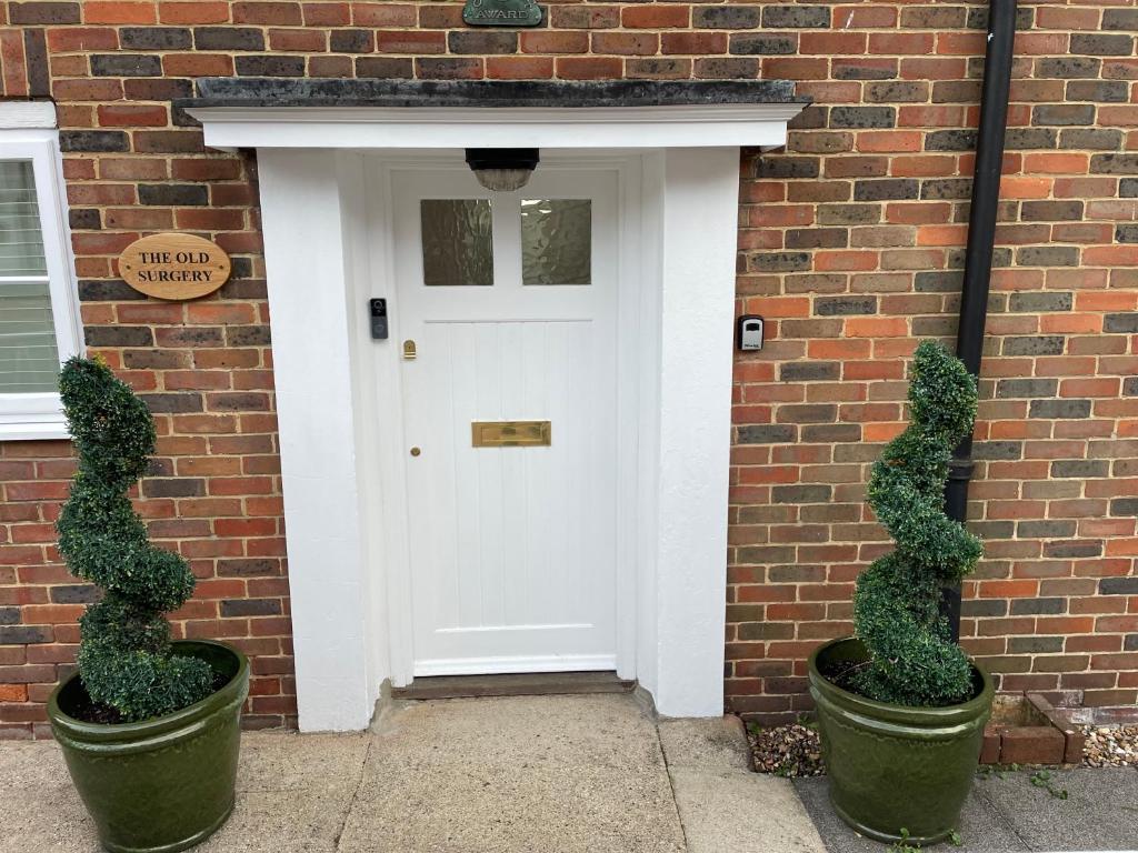 una puerta blanca con 2 plantas frente a un edificio de ladrillo en Luxurious and Elegant Homestay in Kent, en Wrotham