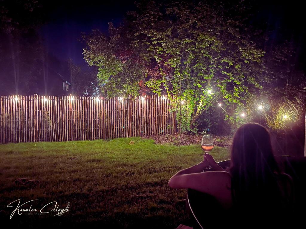 a woman holding a glass of wine in a yard at night at Wellness cottage met hottub 'Auckland' by Kawatea in Ewijk