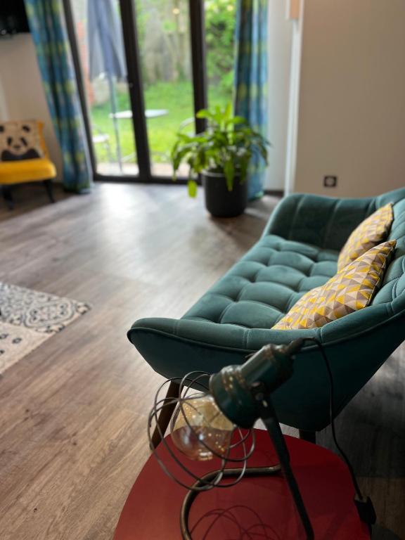 un salon avec un canapé vert et une table dans l'établissement Les Haltes de la Rive Gauche, à Sury-près-Léré