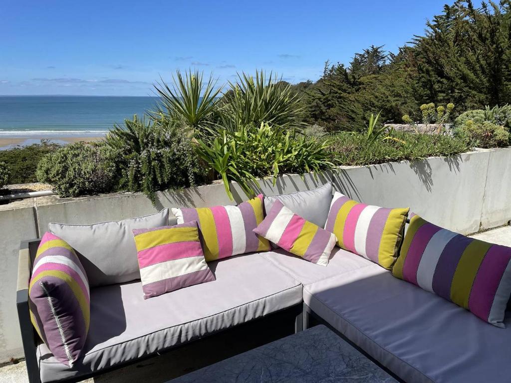 un canapé avec des coussins colorés assis au sommet d'une plage dans l'établissement 489 - Appart T2 surplombant la plage de Caroual., à Erquy