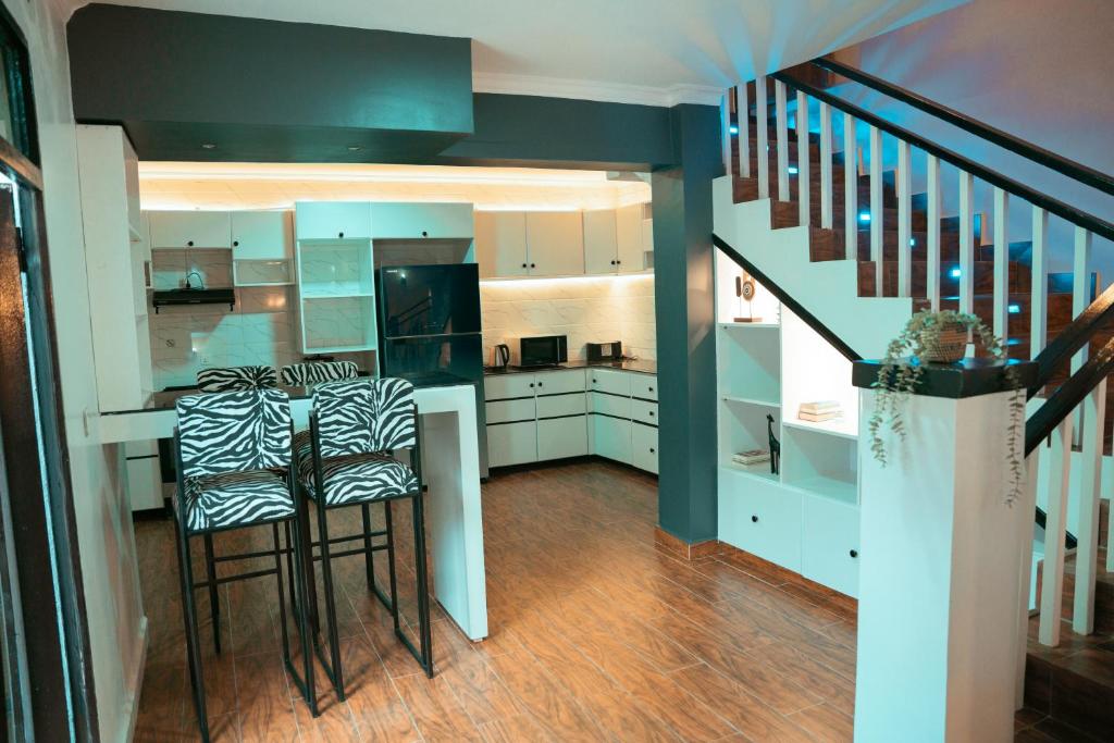 a kitchen with a bar with stools and a staircase at Furnished House at Kibagabaga in Kigali