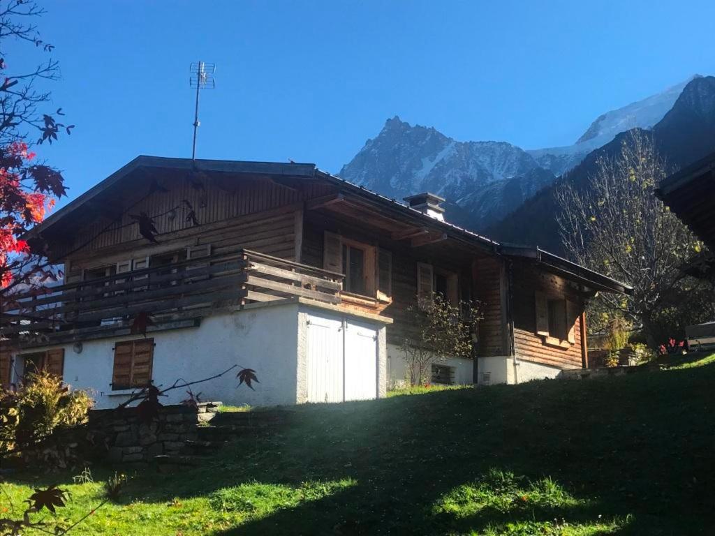 uma casa de madeira numa colina com montanhas ao fundo em Superbe chalet 10 personnes 5 chambres Les Houches em Les Houches