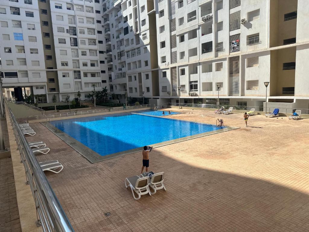 Ein Mann steht neben einem Schwimmbecken in einem Gebäude in der Unterkunft Wood-Finish Home Pool Premium Bedding Self-Check in 7 Min from Marina in Agadir
