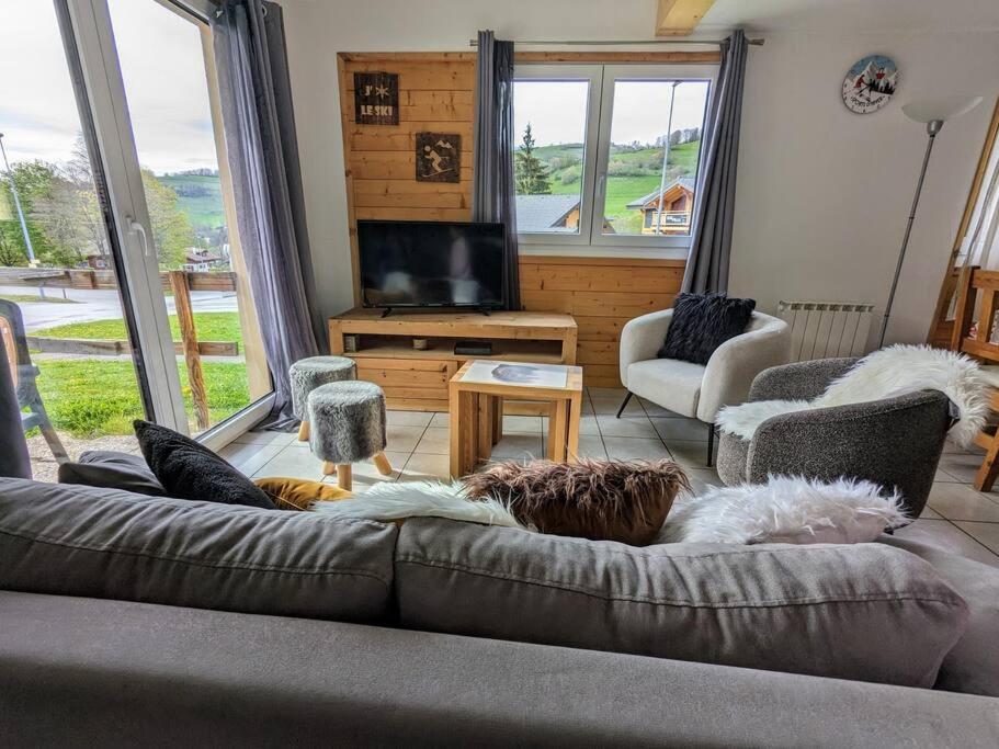 a living room with a couch and a flat screen tv at Spacieux T3 terrasse en rez coeur de station in Bernex