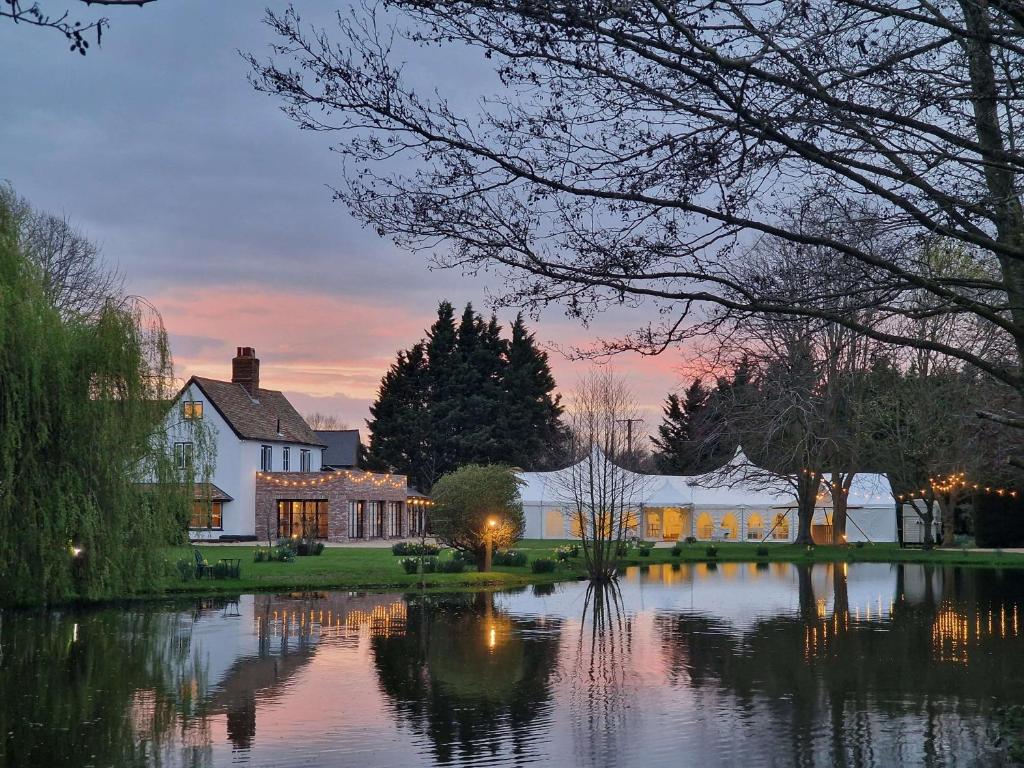 a house sitting next to a lake at dusk at Minstrel Court Wedding Venue in Cambridge