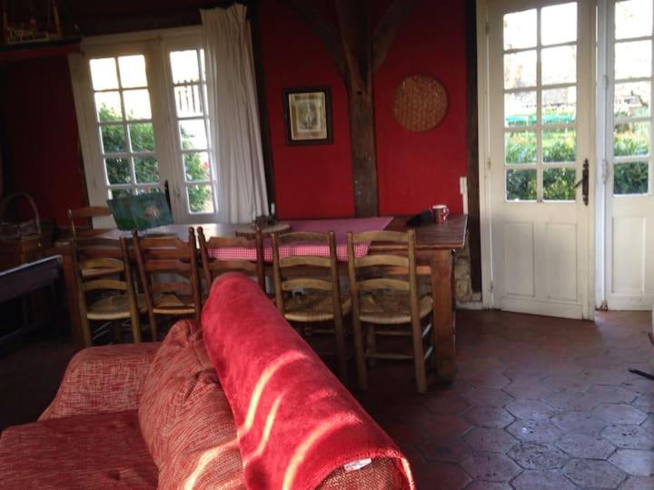- un salon avec une table, des chaises et un mur rouge dans l'établissement Rouge Pivoine, Gîte du Manoir de La Porte, à Les Authieux-sur-Calonne