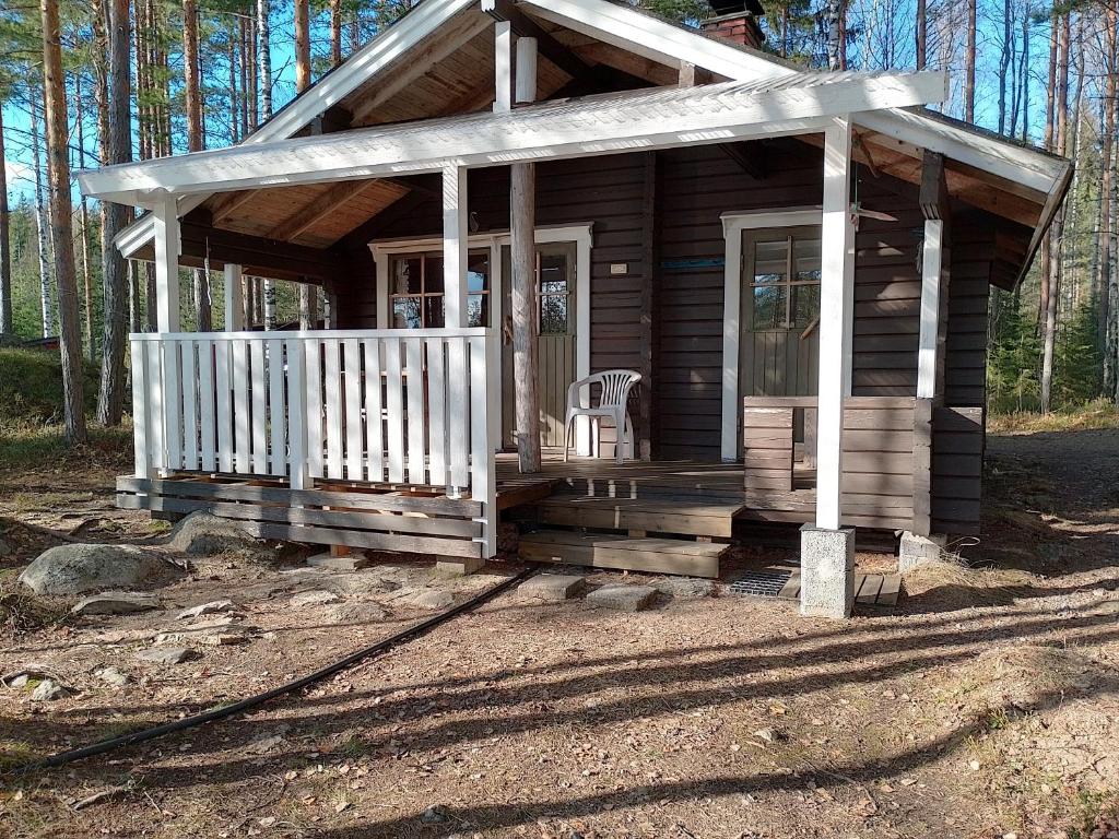 Cabaña de madera pequeña con porche y silla en Kalliomökki, en Puumala