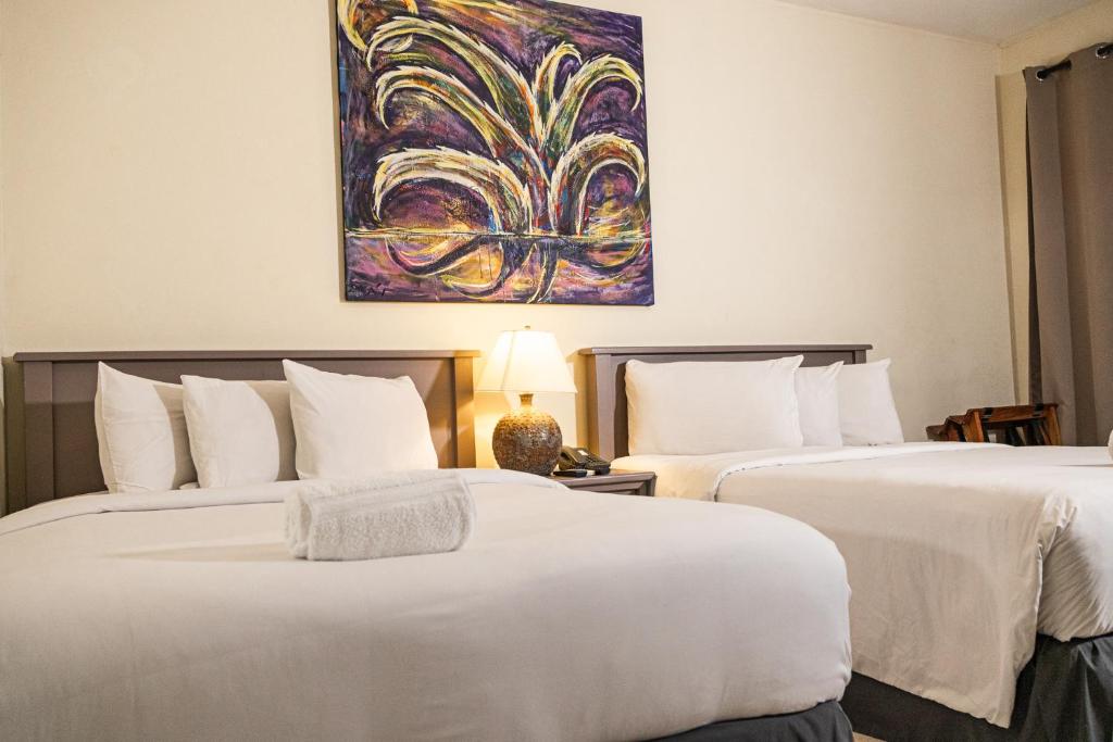 2 camas en una habitación de hotel con un cuadro en la pared en Morrison Hotel de la Escalon, en San Salvador