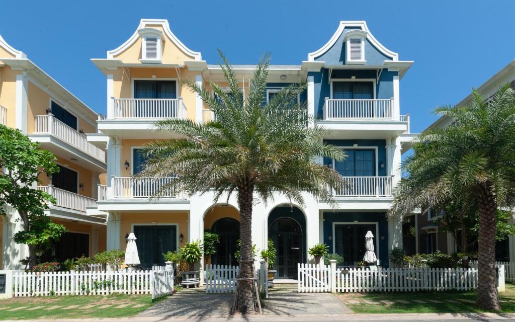 a large white building with palm trees in front of it at NovaWonderland Ho Tram Villa in Xuyên Mộc