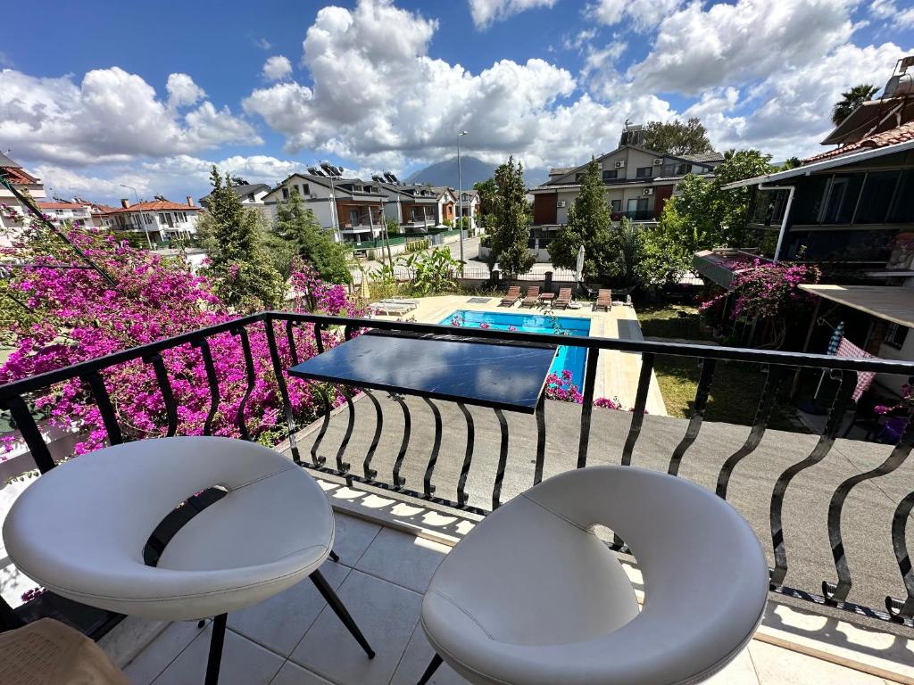 a balcony with two white chairs and a pool at Suit Fiona in Fethiye