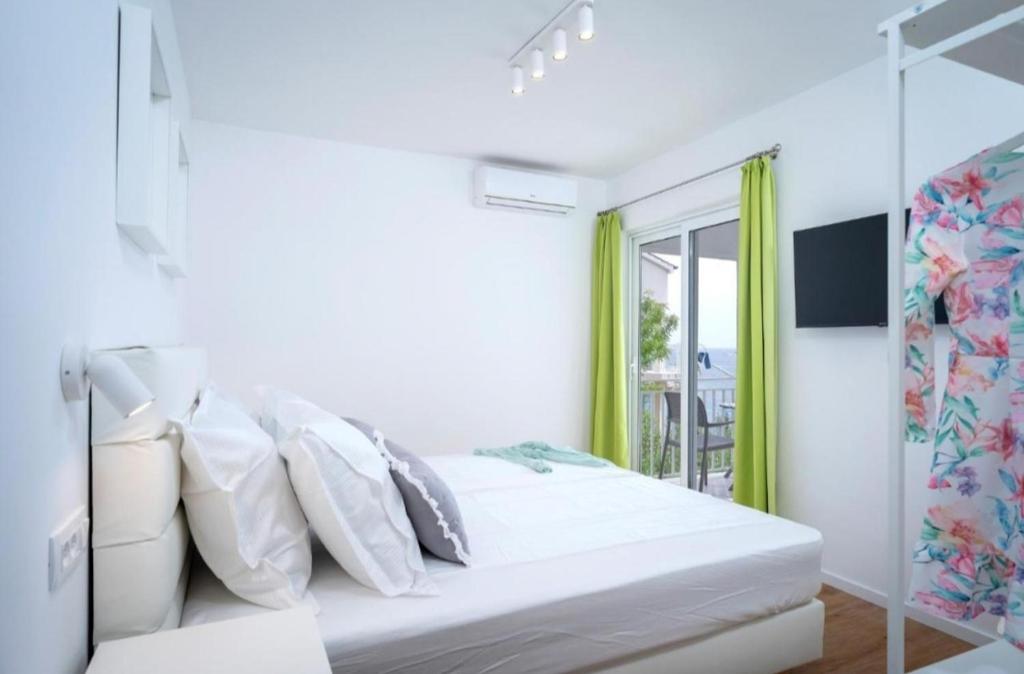 a white bedroom with a bed and a window at Blue Lagoon house in Hvar
