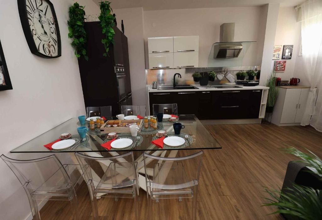 uma cozinha com uma mesa de vidro e cadeiras num quarto em SWEET HOME FIERA em Bolonha