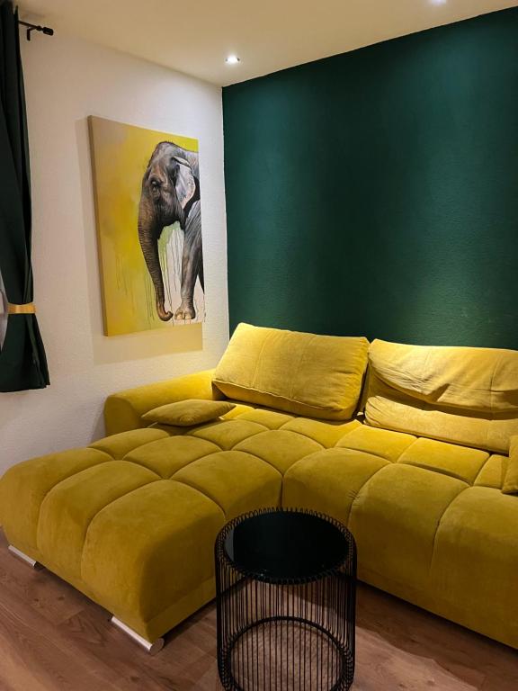 a living room with a yellow couch and an elephant painting at Gemütliches 3 Zimmer Apartment nahe Science Park in Blaustein