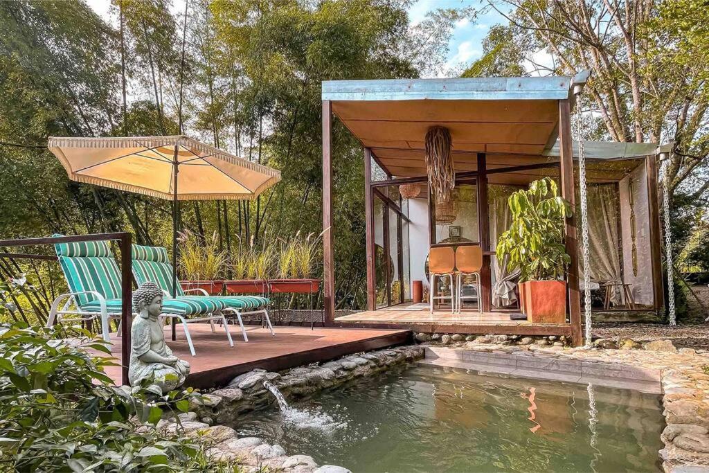 a house with a pool of water in front of a house at Intrepido Glamping in Chinchiná