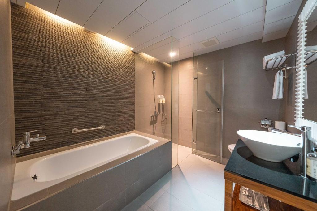 a bathroom with a bath tub and a sink at Hotel Cloud Riverside in Tamsui