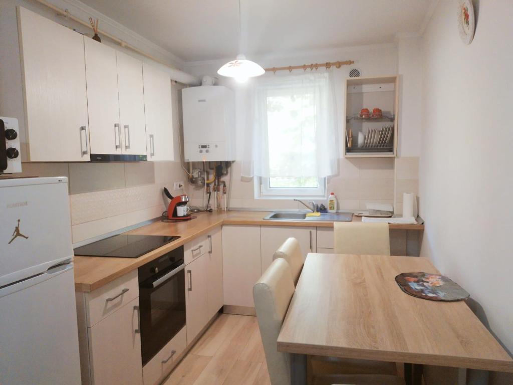 Una cocina con gabinetes blancos y una mesa de madera. en Gold Apartments, en Baia Mare