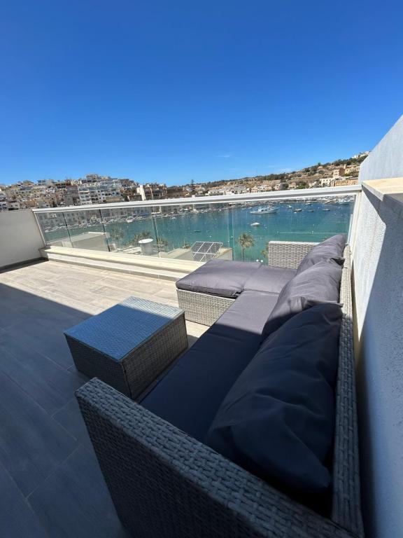 d'un balcon avec un canapé et une vue sur l'eau. dans l'établissement Seaview Setters Penthouse Marsaskala, à Marsaskala