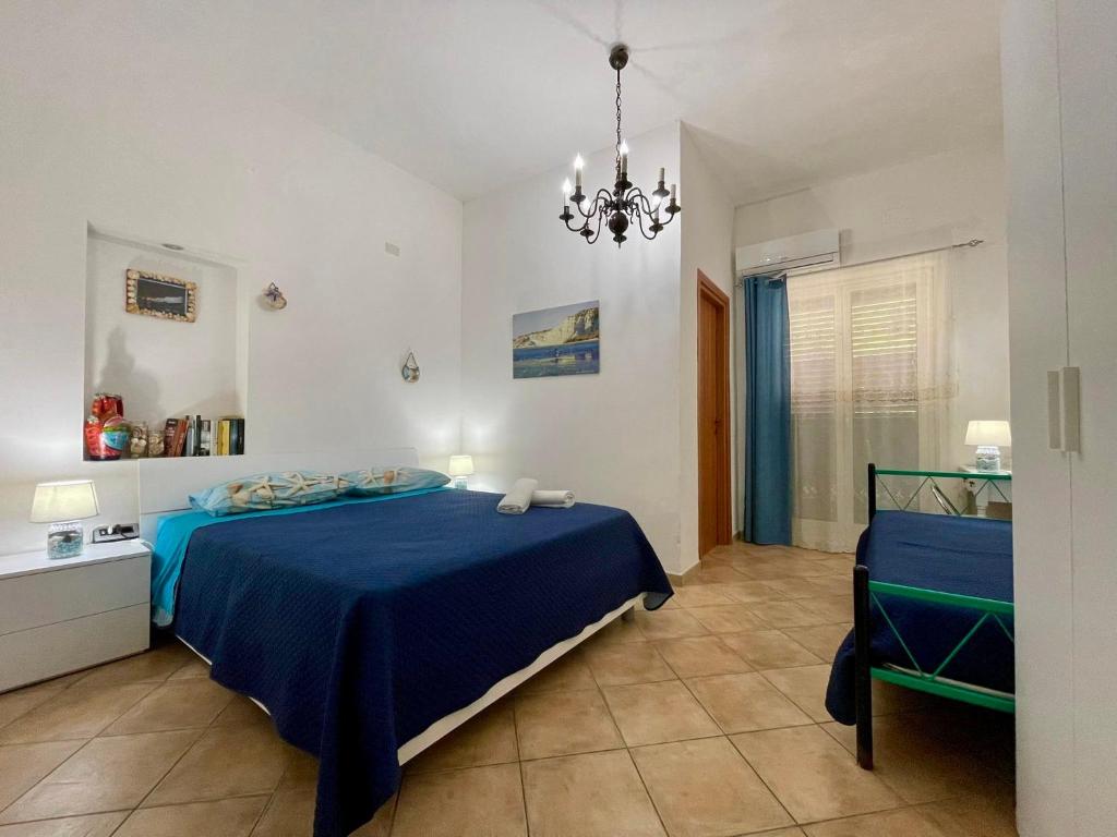 Un dormitorio con una cama azul y una lámpara de araña. en B&B Scala dei Turchi Beach, en Realmonte