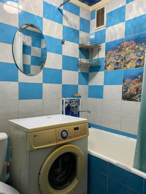 a bathroom with a washing machine and a tub at Однокомнатная квартира in Shymkent