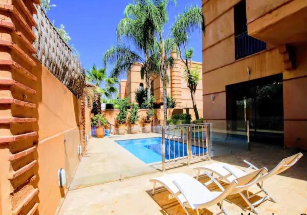 une terrasse avec des chaises blanches et une piscine dans l'établissement Villa-Marrakech, à Marrakech