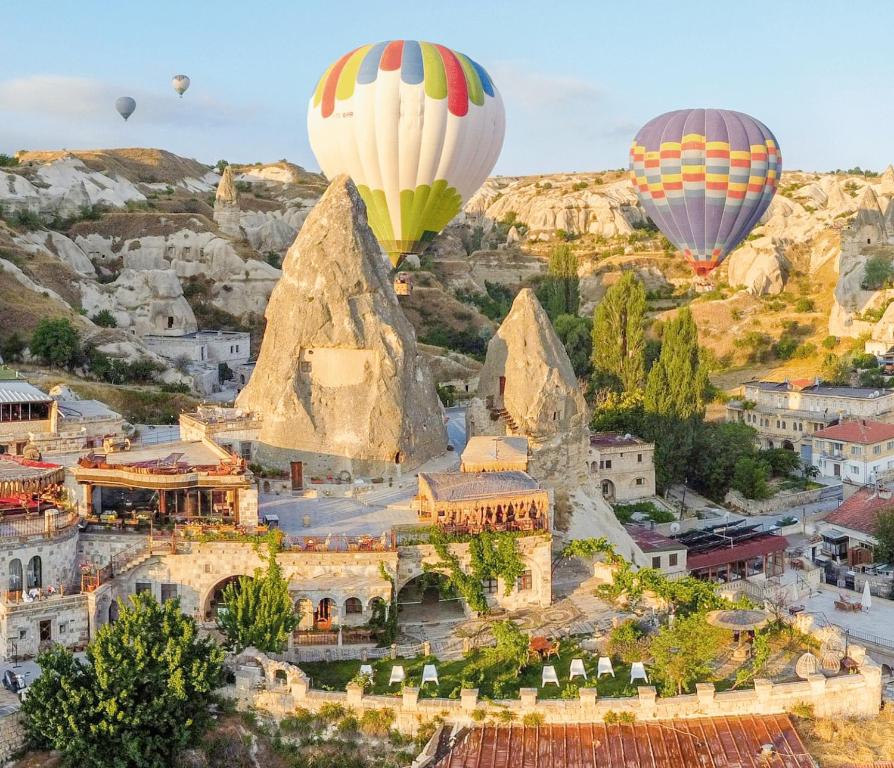 un groupe de montgolfières survolant une ville dans l'établissement Panoramic Cave Hotel & SPA, à Gorëme