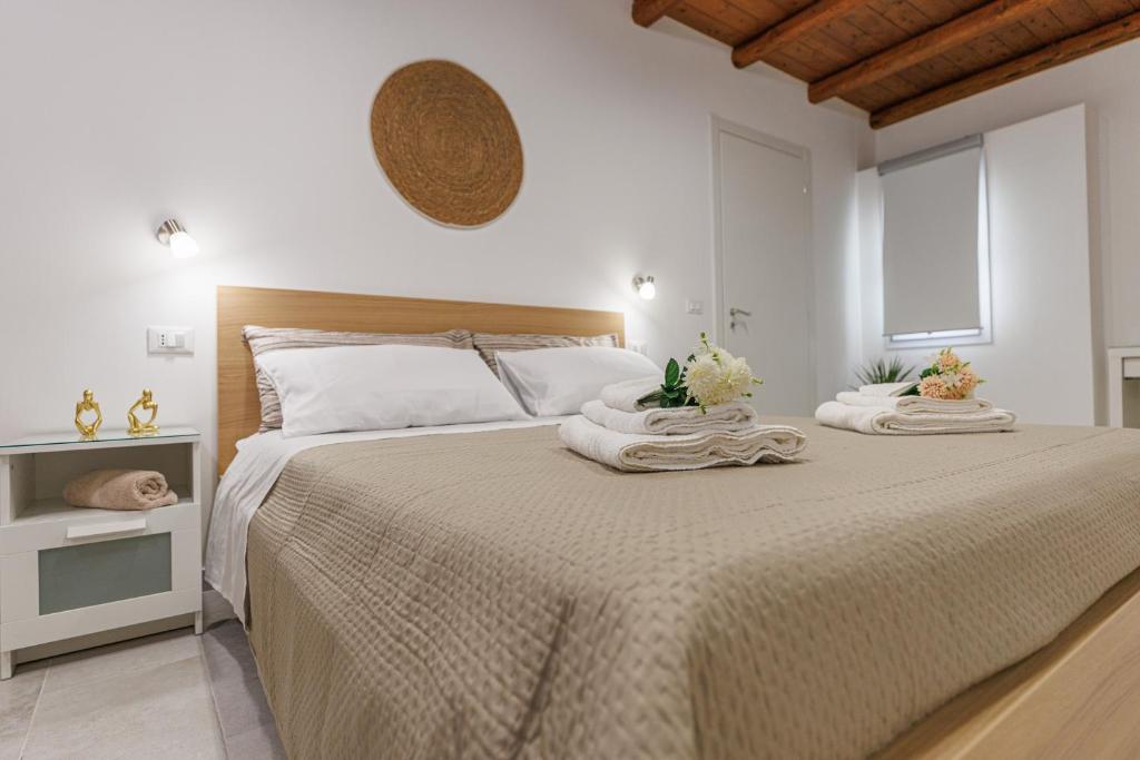 ein weißes Schlafzimmer mit einem großen Bett mit Handtüchern darauf in der Unterkunft Al Cortiletto in Avola