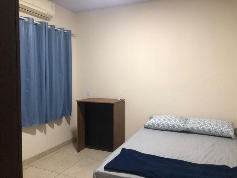 a bedroom with a bed and a blue curtain at Wm Milão in Sinop