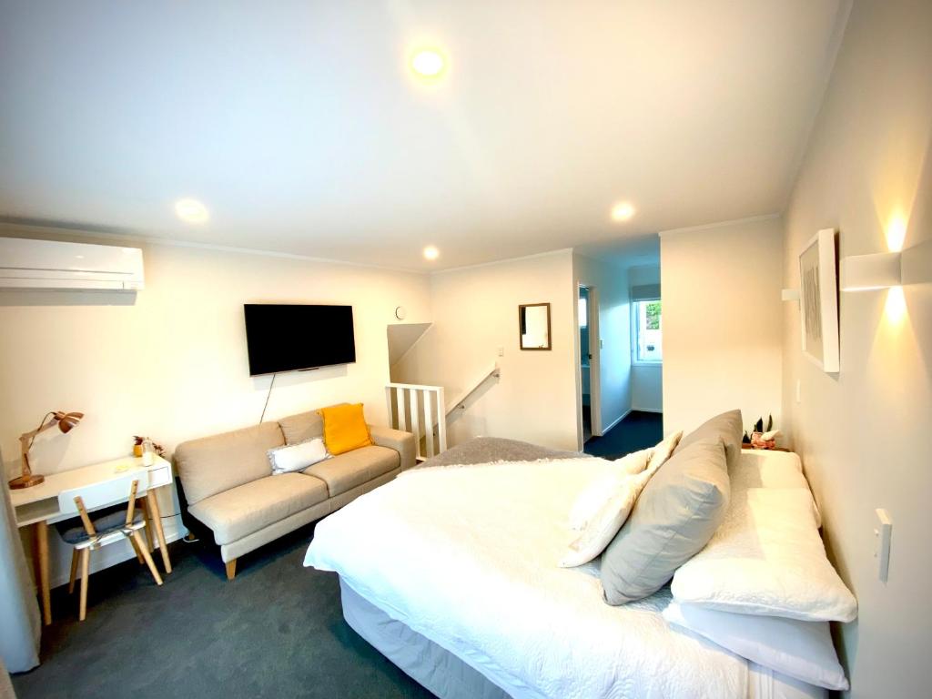 a bedroom with a bed and a couch and a tv at 2 Mile Bay Guesthouse in Taupo