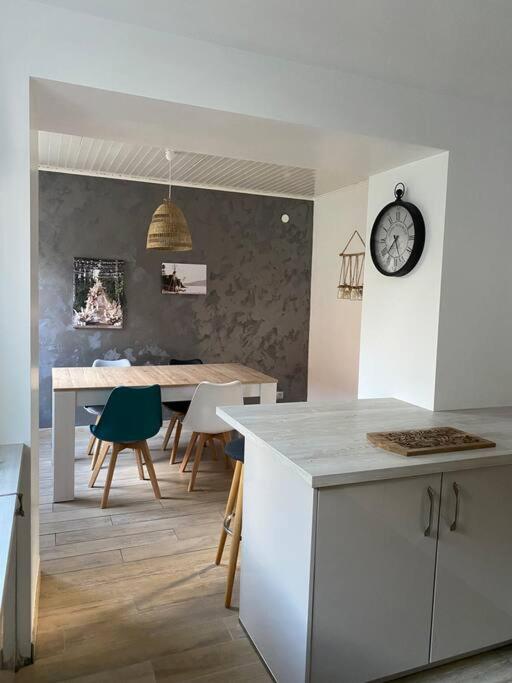 une cuisine avec une table et une horloge au mur dans l'établissement Gîte - Le cocon de la Marquise, à Wattwiller