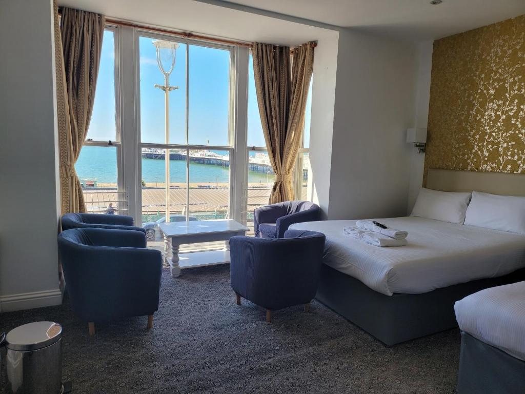 a hotel room with a bed and chairs and a large window at Atlantic Seafront in Brighton & Hove