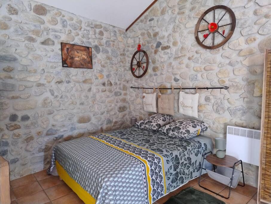 a bedroom with a bed and a stone wall at lou caladou gîte en pierre avec bain à remous in Vallon-Pont-dʼArc