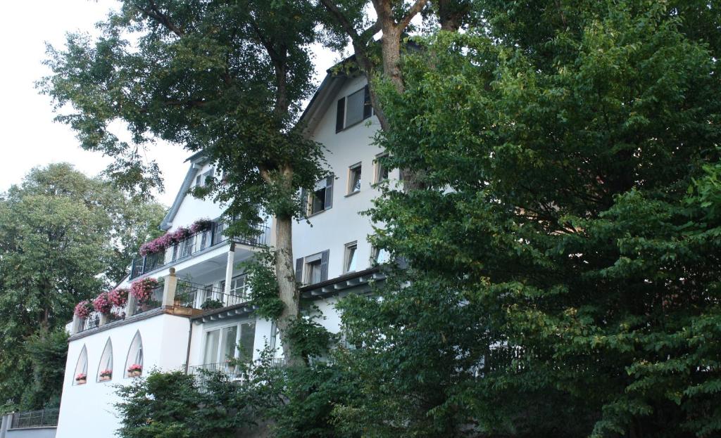 ein weißes Gebäude mit einem Balkon mit Blumen darauf in der Unterkunft Altes Kurhaus Landhotel in Trabelsdorf