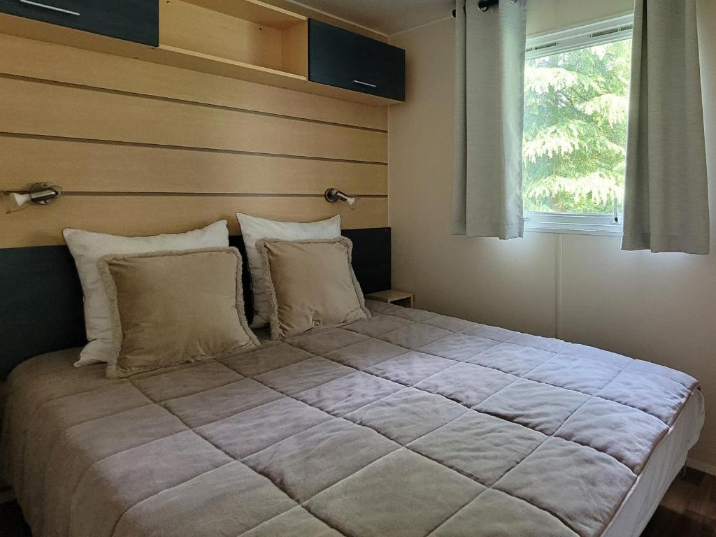 a large bed in a room with a window at MobilHome Nicolette EUROPAPARK 20min in Boofzheim