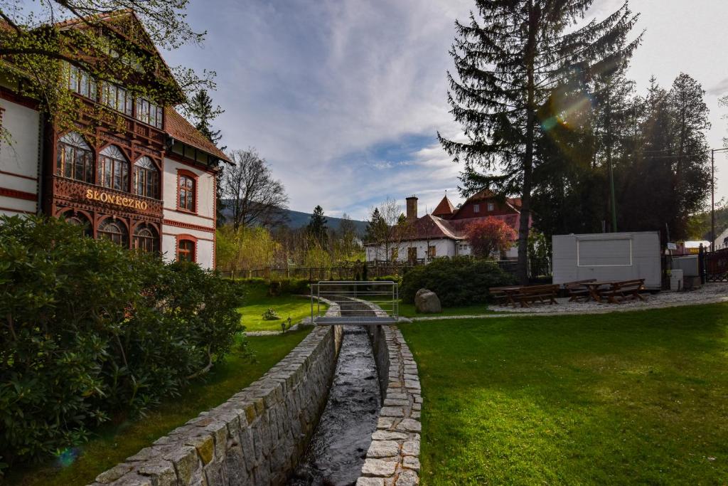 a house with a stone wall and a bench in a yard at Willa Słoneczko in Szklarska Poręba