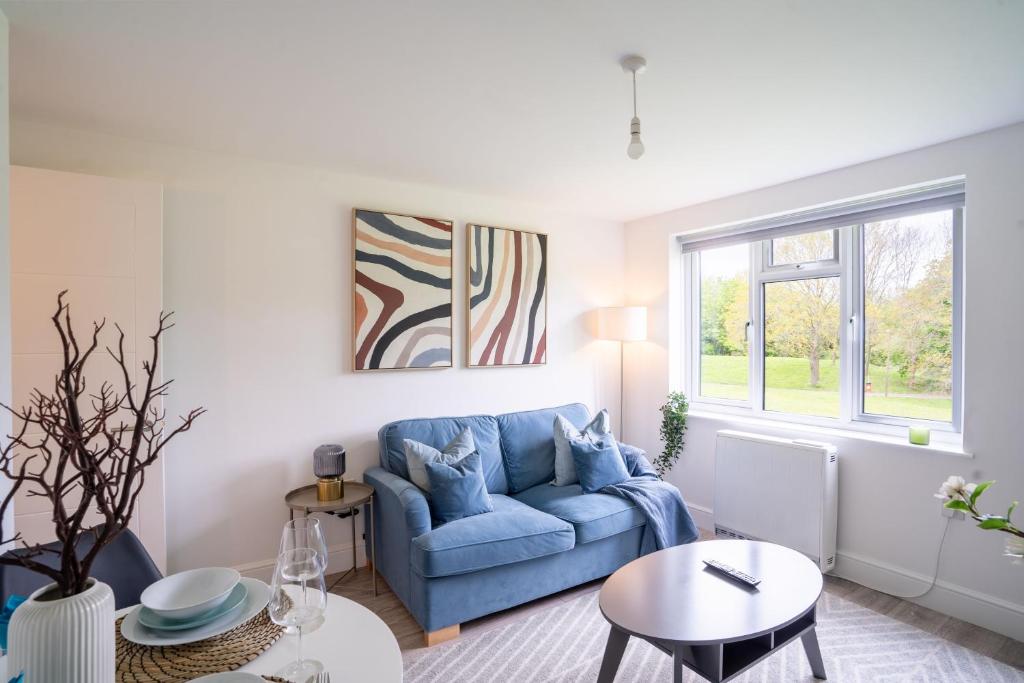 a living room with a blue couch and a table at Modern Apt with Free Parking & Park Views in MK in Woolstone