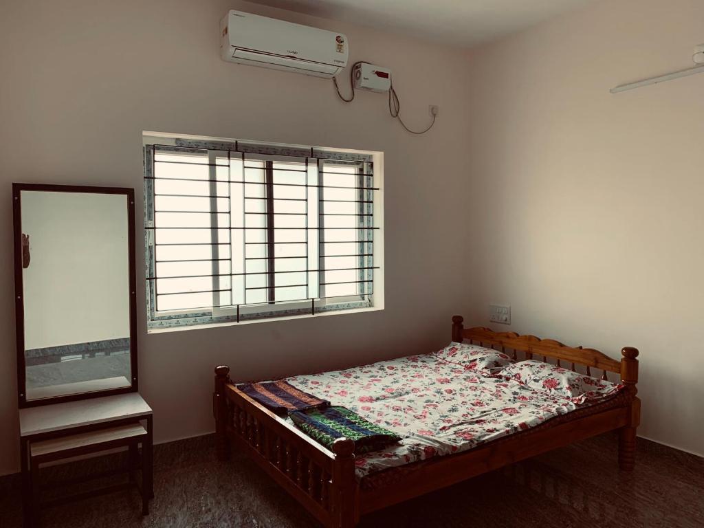 a bedroom with a bed and a mirror and a window at Honnavar Pauli s Homestay in Honāvar