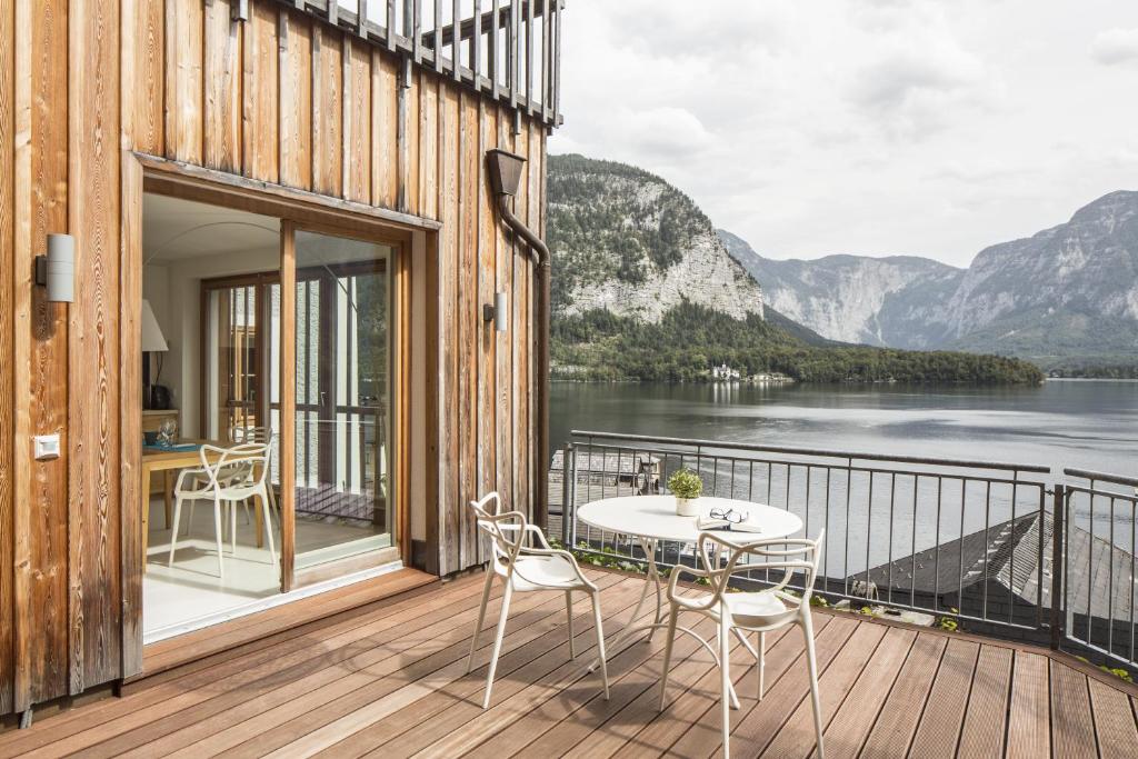 een balkon met een tafel en stoelen en uitzicht op een meer bij Hallstatt Hideaway - Adults only in Hallstatt