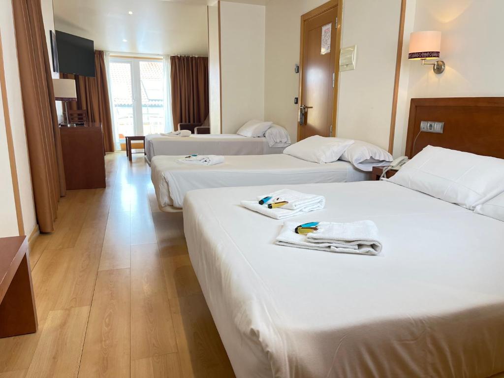 フィニステレにあるHotel Spa Playa Langosteira by Adelolóのホテルルーム ベッド3台(タオル付)