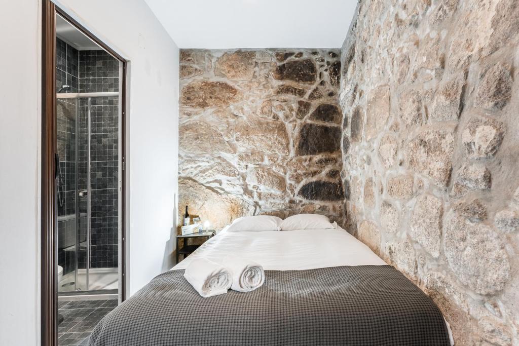 a bedroom with a stone wall and a bed at Sao Victor Suites in Porto