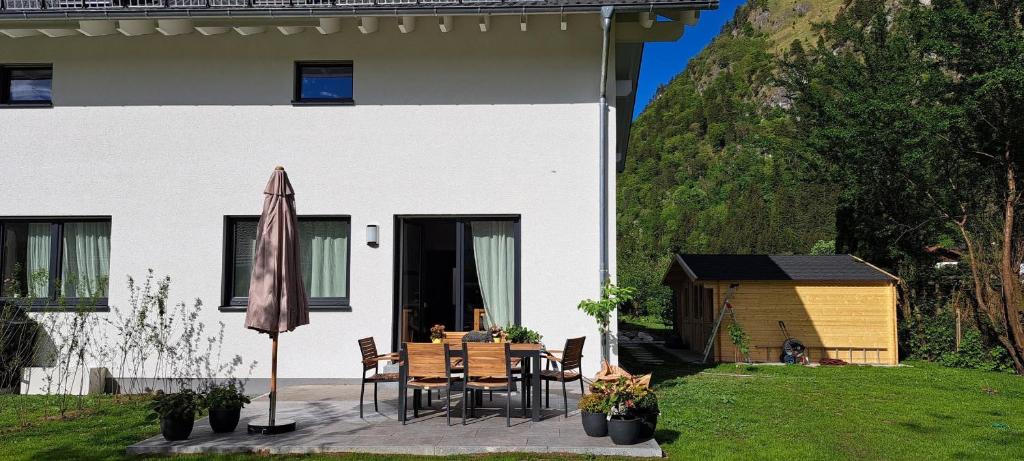 a patio with a table and an umbrella in front of a house at Ferienhaus Baron mit eigener Sauna in Marquartstein