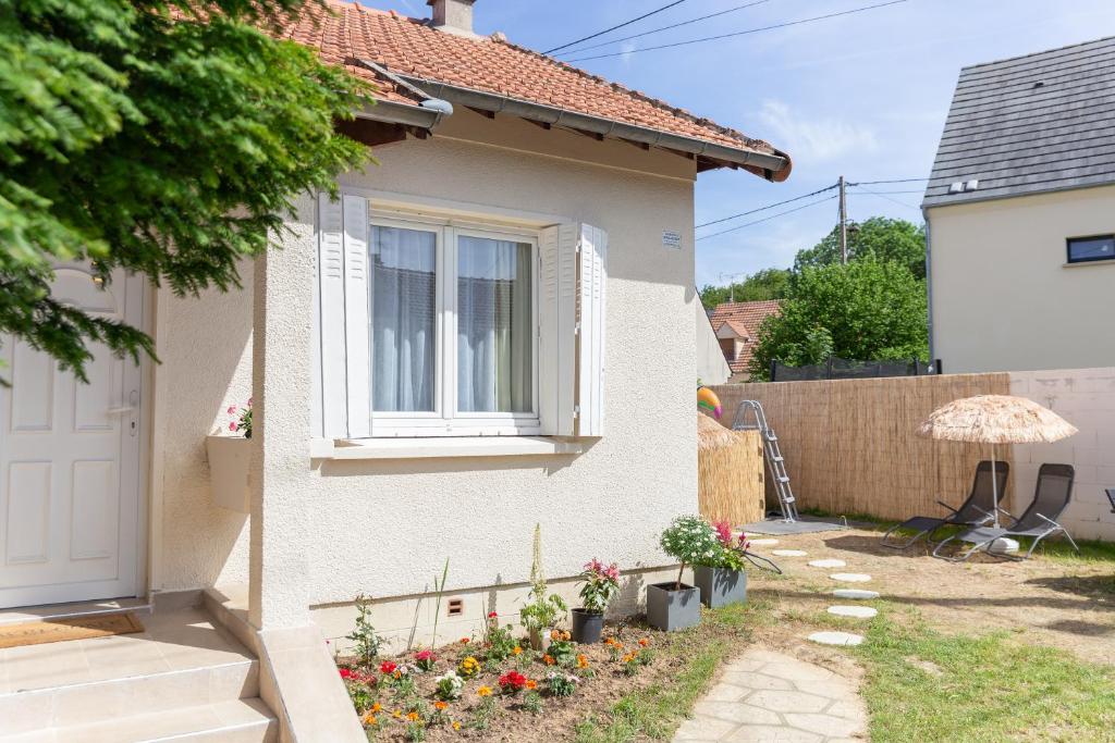 une maison blanche avec une fenêtre et une clôture dans l'établissement La maison du bonheur - CDG & parc des expos - piscine privée, à Villepinte
