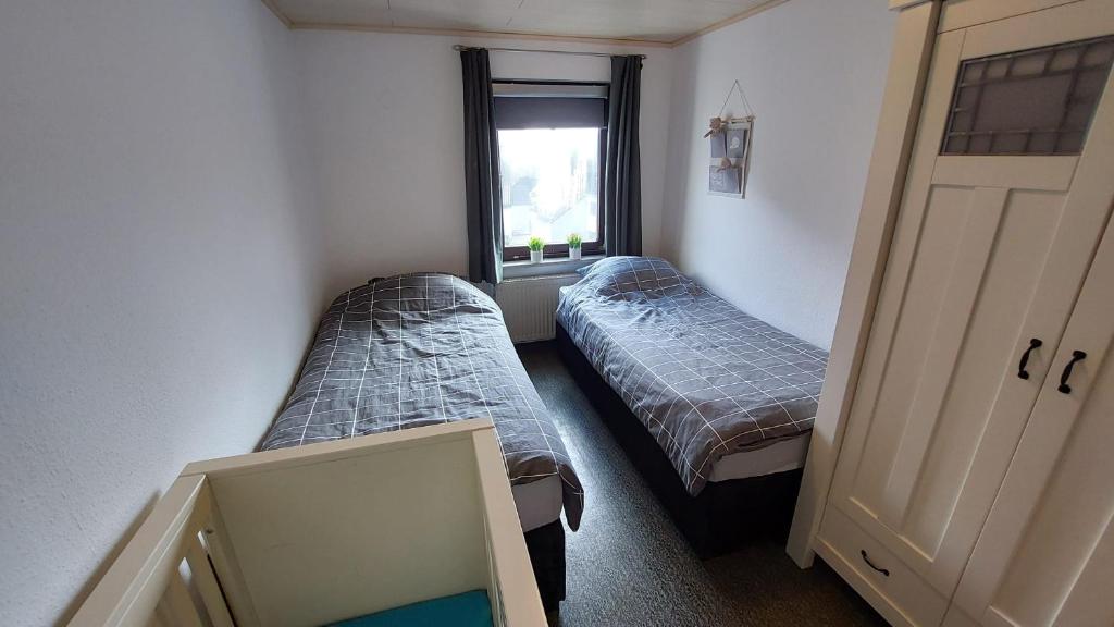 2 Betten in einem kleinen Zimmer mit Fenster in der Unterkunft Feriënhaus Hohe Acht in Siebenbach