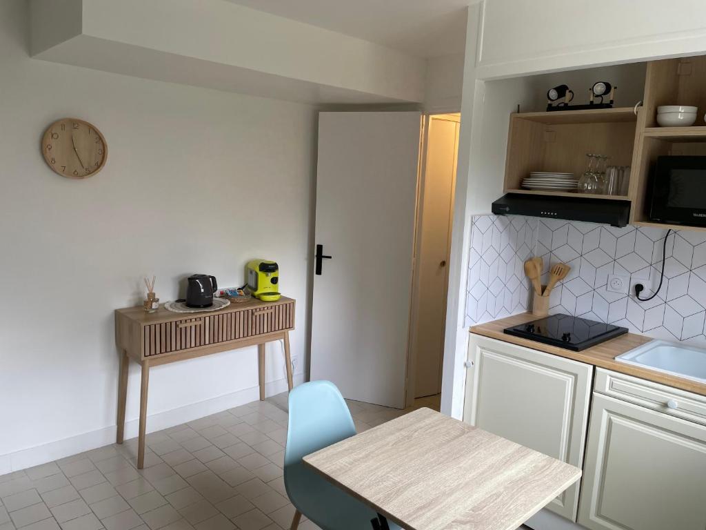 une cuisine avec une table et une petite table et une horloge dans l'établissement L’Odyssée, à Blonville-sur-Mer