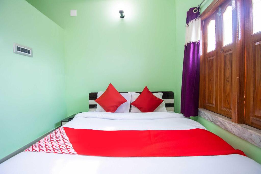 a bedroom with a bed with red pillows at OYO Hotel Taj International in Baharampur