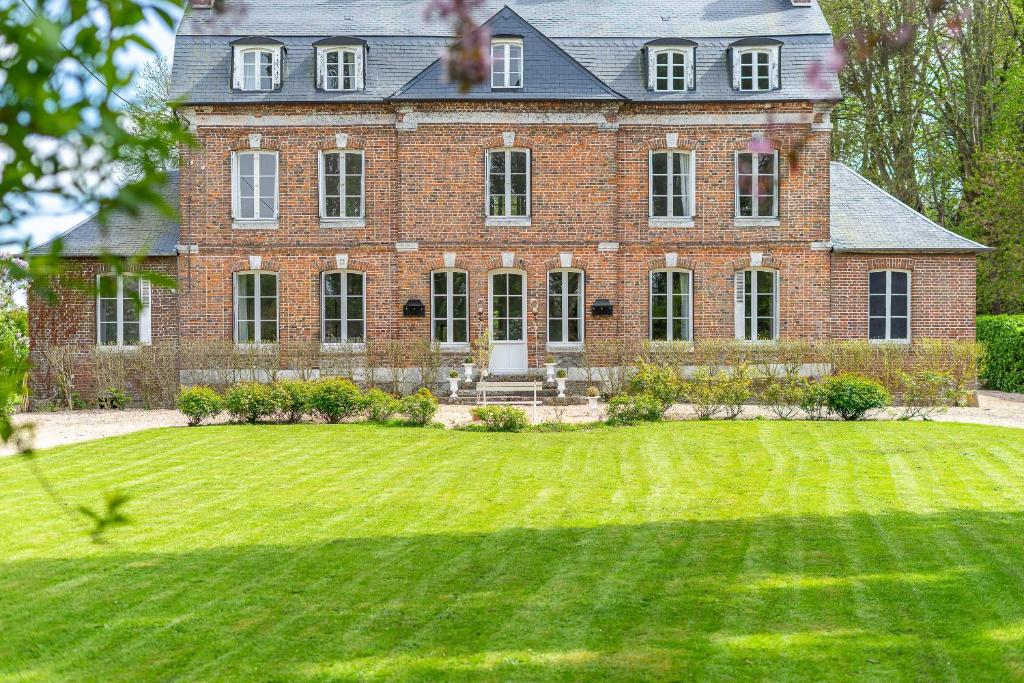 uma grande casa de tijolos com um grande jardim de relva em La Prévôté de Grainville - Manoir normand du XVIIIe siècle em Grainville