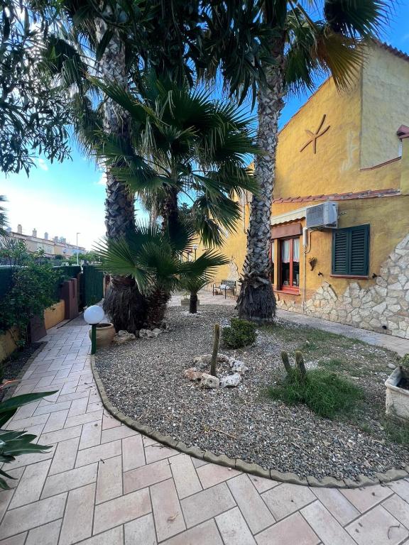 a courtyard with palm trees in front of a building at Villa Azzurra Fronte Mare in Capitana